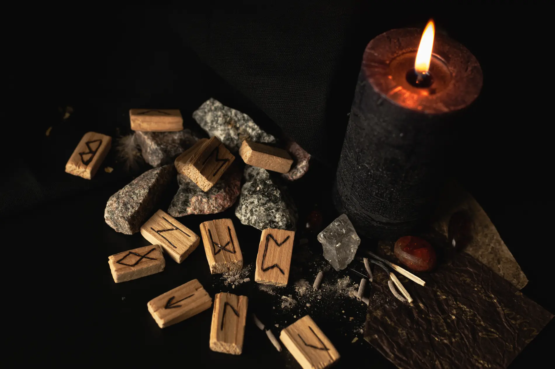 Rituel chamanique avec runes en bois, bougies et pierres sur fond sombre